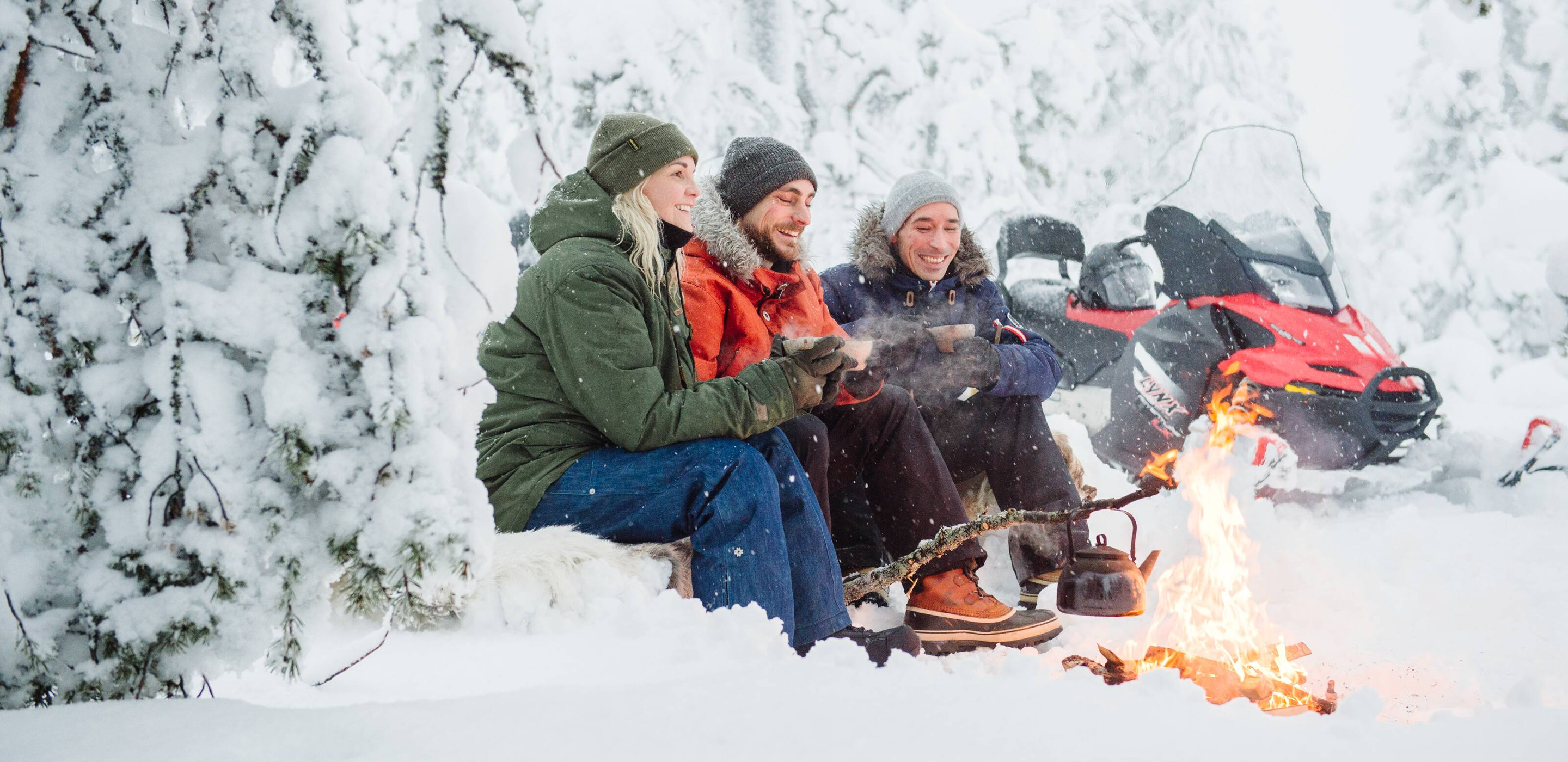 Schneemobil Pause bei Lagerfeuer